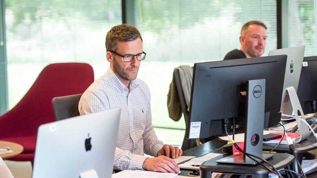 Twee mannen uit een zakelijke organisatie die werken met data achter hun eigen computerscherm